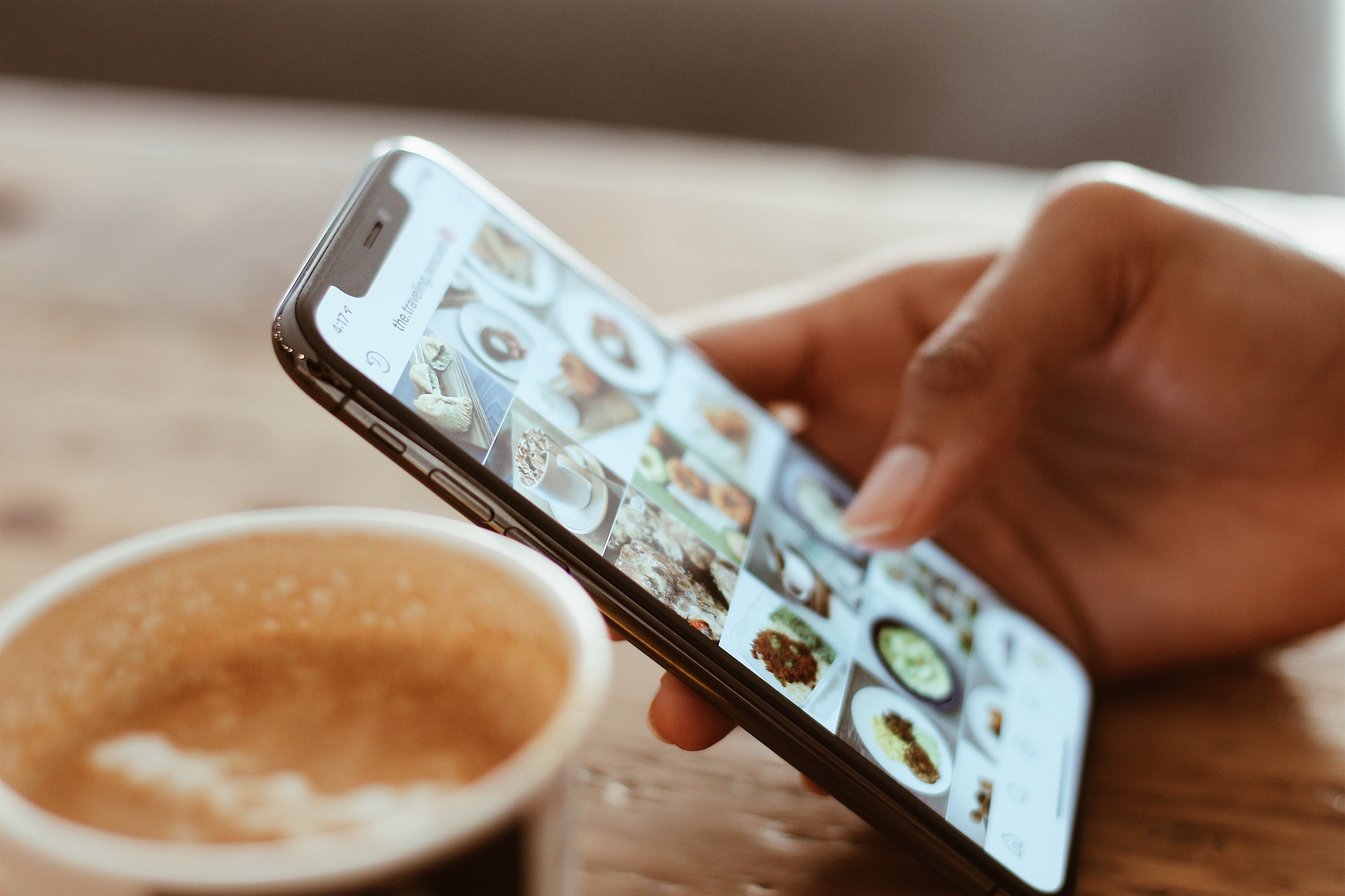 Social media marketing calgary picture of a phone someone on instagram with a coffee next to them