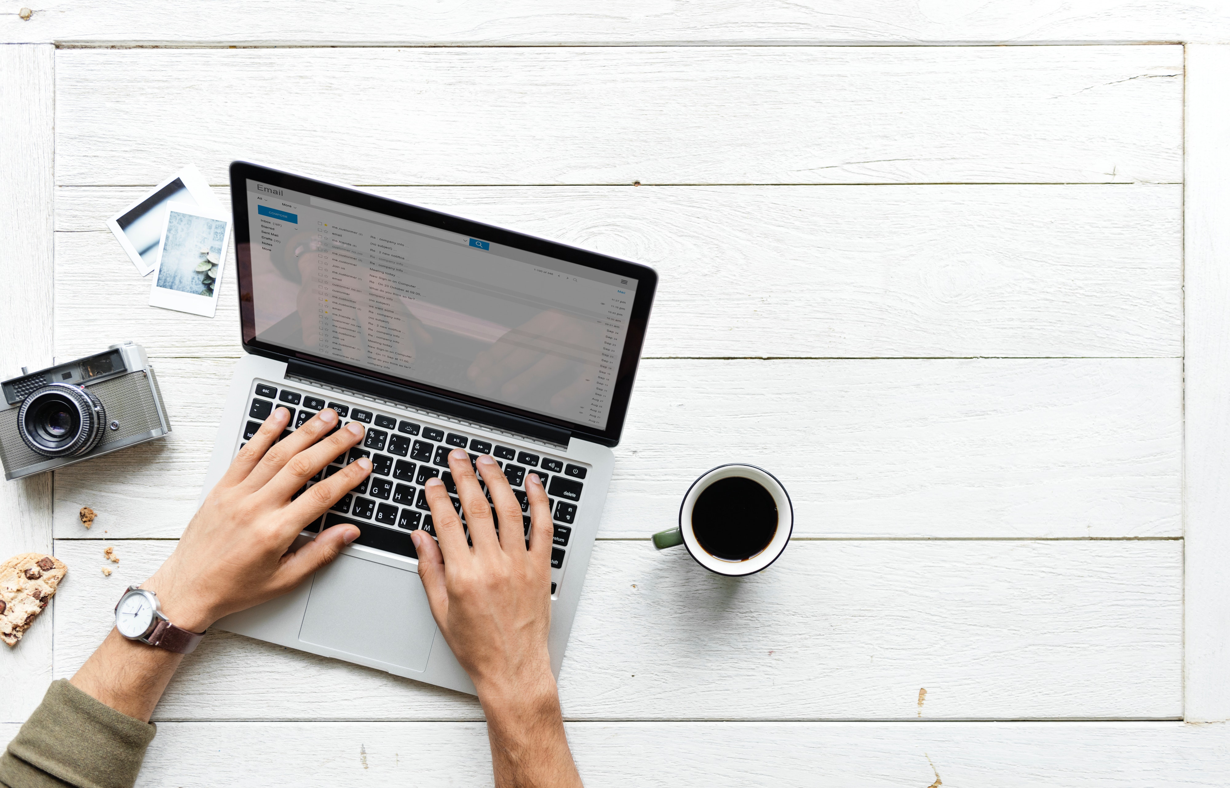 Top down view of a laptop with a black coffee and hands typing on social media